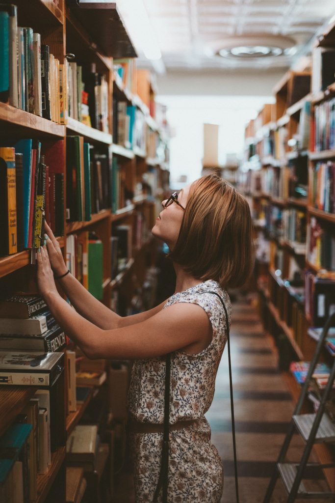 woman looking for a book in an isle at the library