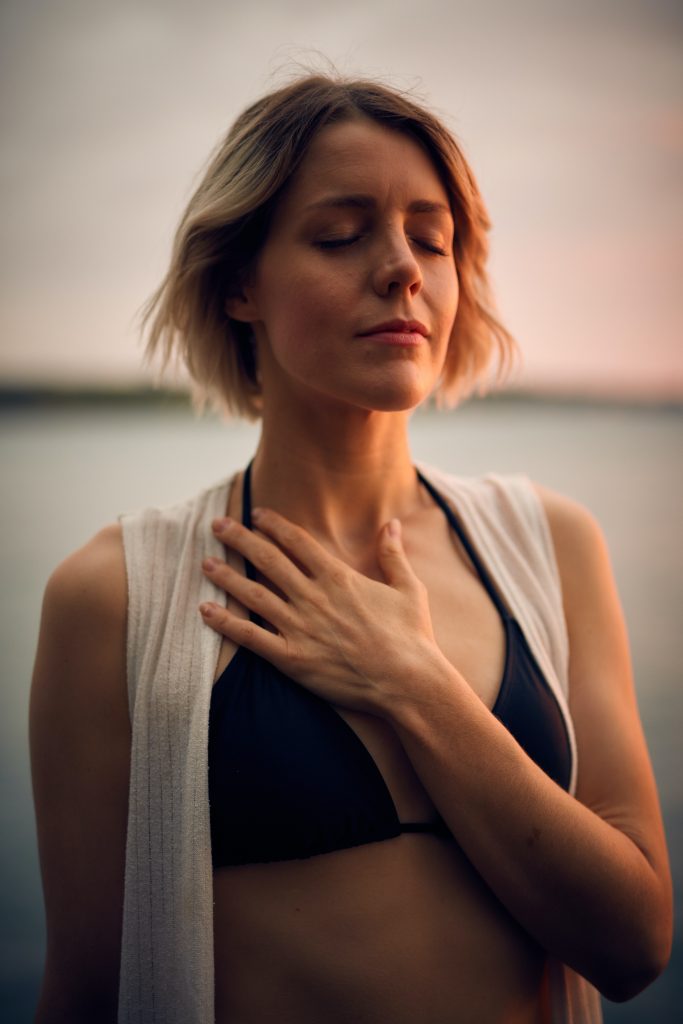 woman with her eyes closed holding her hand on her chest