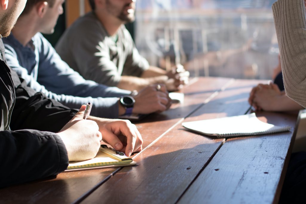 men taking notes on a pad sitting at a table together