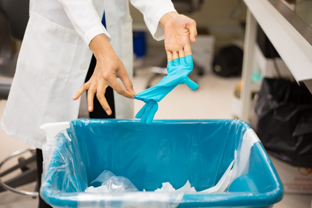 blue disposable latex gloves getting thrown in the bin